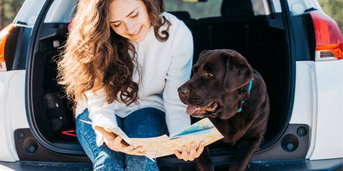 Women and chocolate Labrador retriever reading a map of where they are going next on their journey