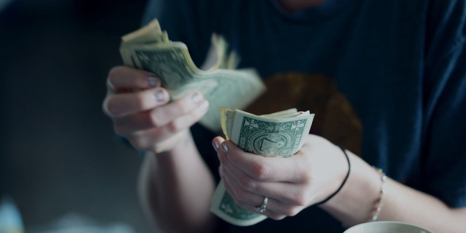 Torso of person counting one-dollar bills