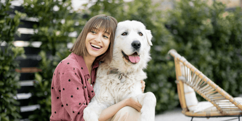 Happy woman smiling and hugging long-haired white dog