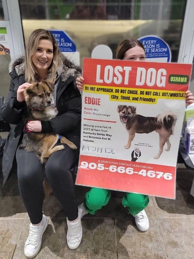 Eddie with his family and girl holding his lost dog poster after he was found