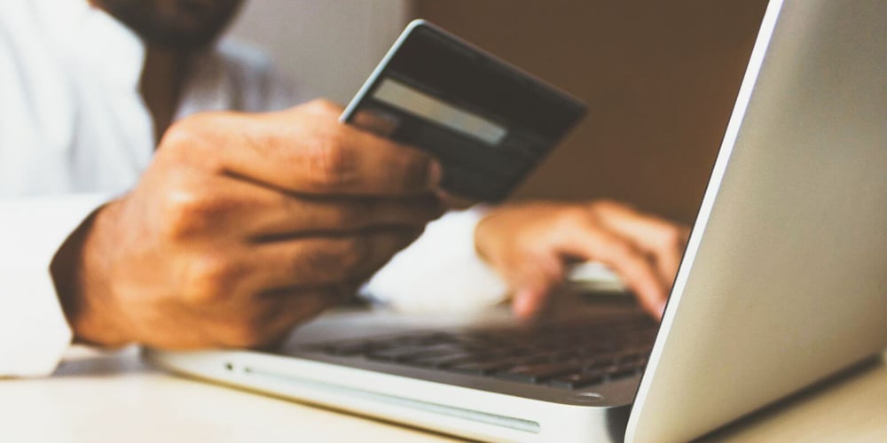 Man sitting at laptop paying with credit card